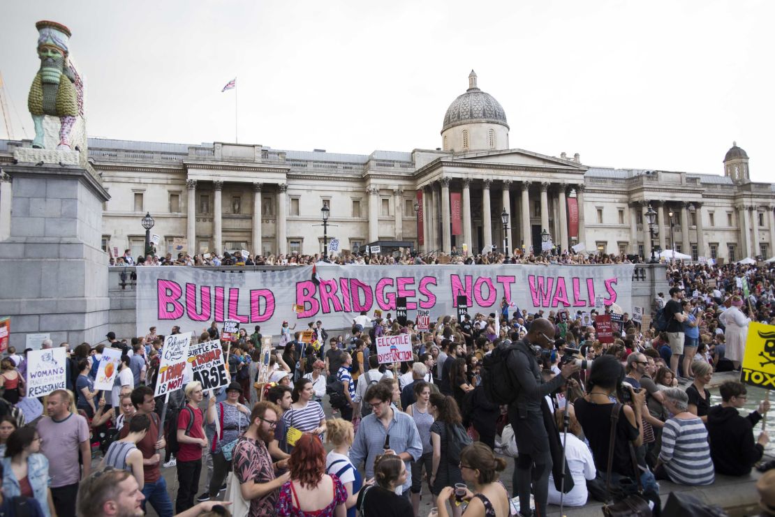 Crowds rally in Trafalgar Square, where a giant banner reads: "Build bridges not walls."