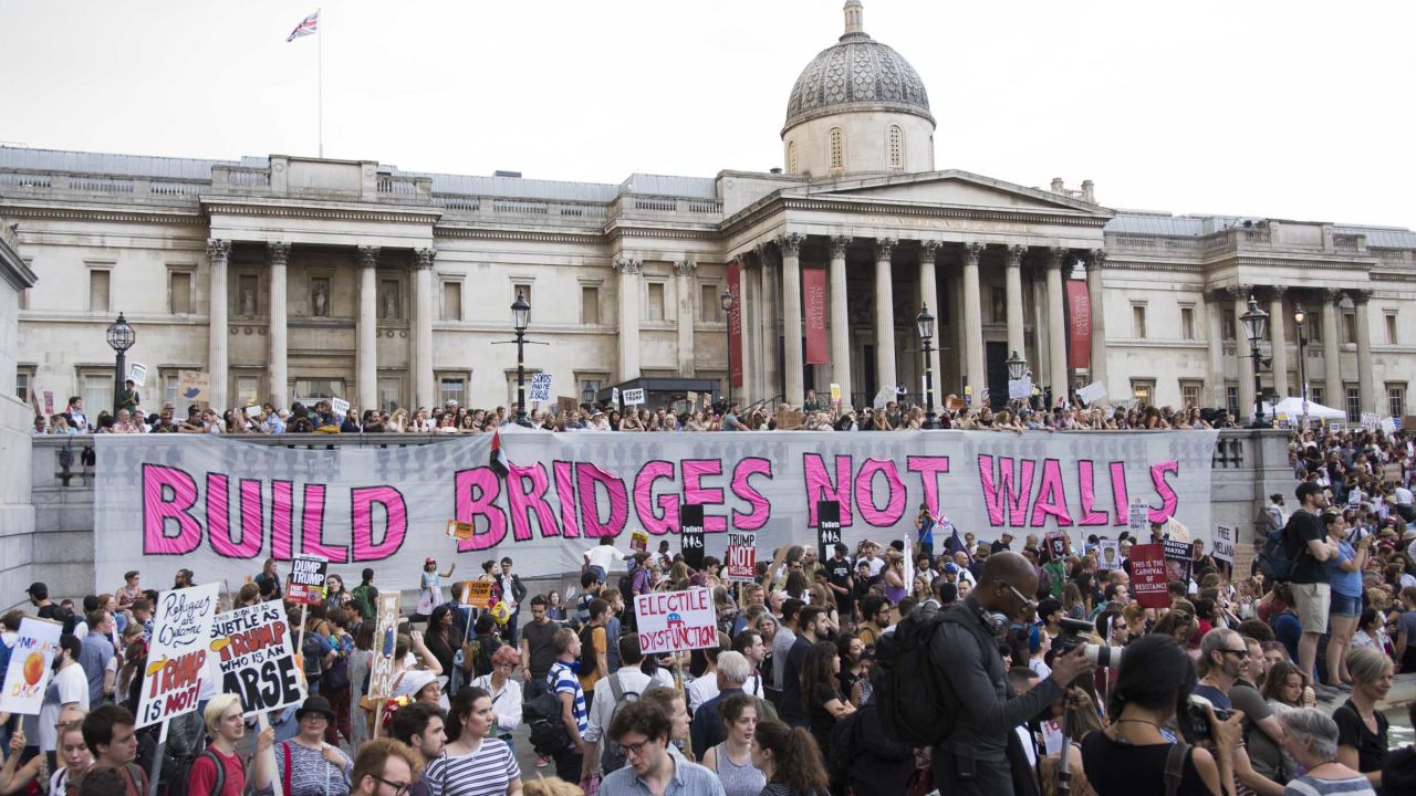 Crowds rally in Trafalgar Square, where a giant banner reads: "Build bridges not walls."
