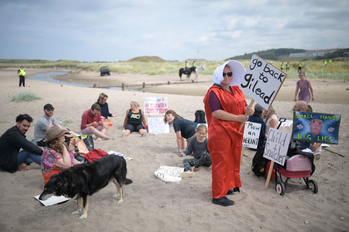 A woman wears a costume in the style of the "Handmaid's Tale" on a beach near Turnberry.