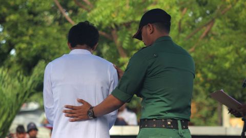 An official checks on a convicted offender during the public flogging.