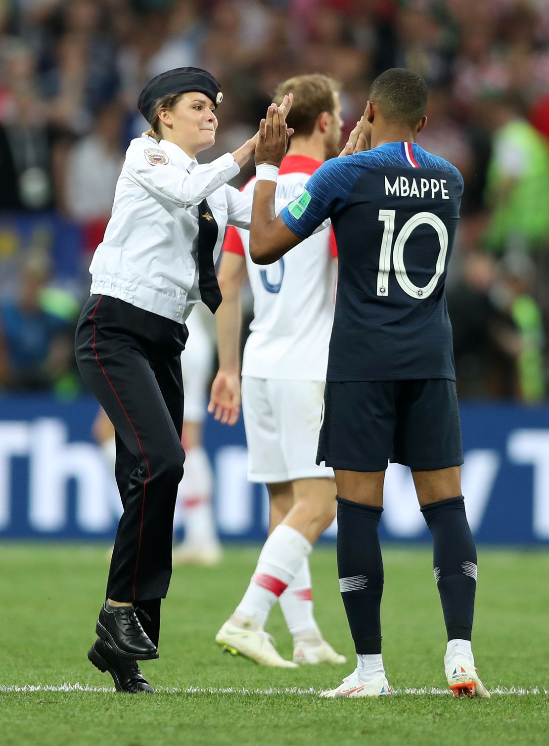 A pitch invader high fives Kylian Mbappe.