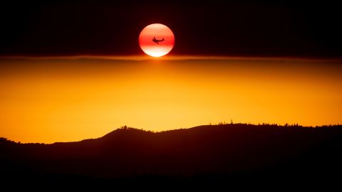 A plane battling the Ferguson Fire passes the setting sun near Yosemite National Park on Sunday.