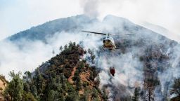 A helicopter gathers water from the Merced River to fight the Ferguson Fire along steep terrain behind the Redbud Lodge near El Portal along Highway 140 in Mariposa County, Calif., on Saturday, July 14, 2018. (Andrew Kuhn/The Merced Sun-Star via AP)
