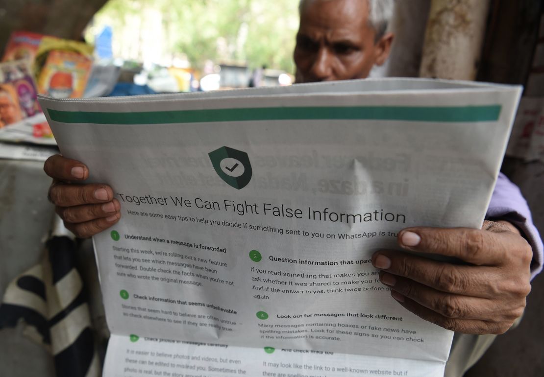 This photo illustration shows an Indian newspaper vendor reading a newspaper with a full back page advertisement from WhatsApp intended to counter fake information, in New Delhi on July 10, 2018.