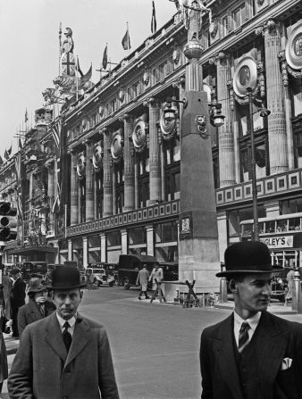 Men walk by Selfridges department store on Oxford Street. 