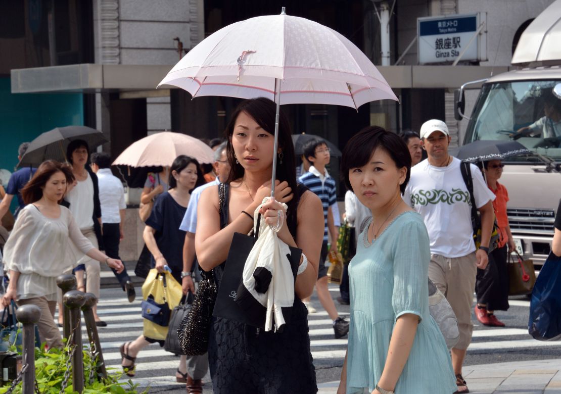 Pedestrians use their parasols to avoid strong sunlight in Tokyo on July 12.