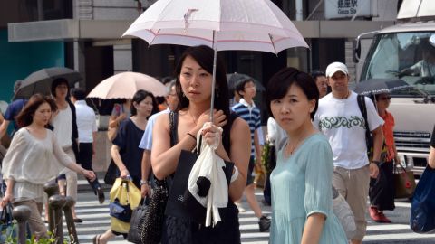 Pedestrians use their parasols to avoid strong sunlight in Tokyo on July 12.