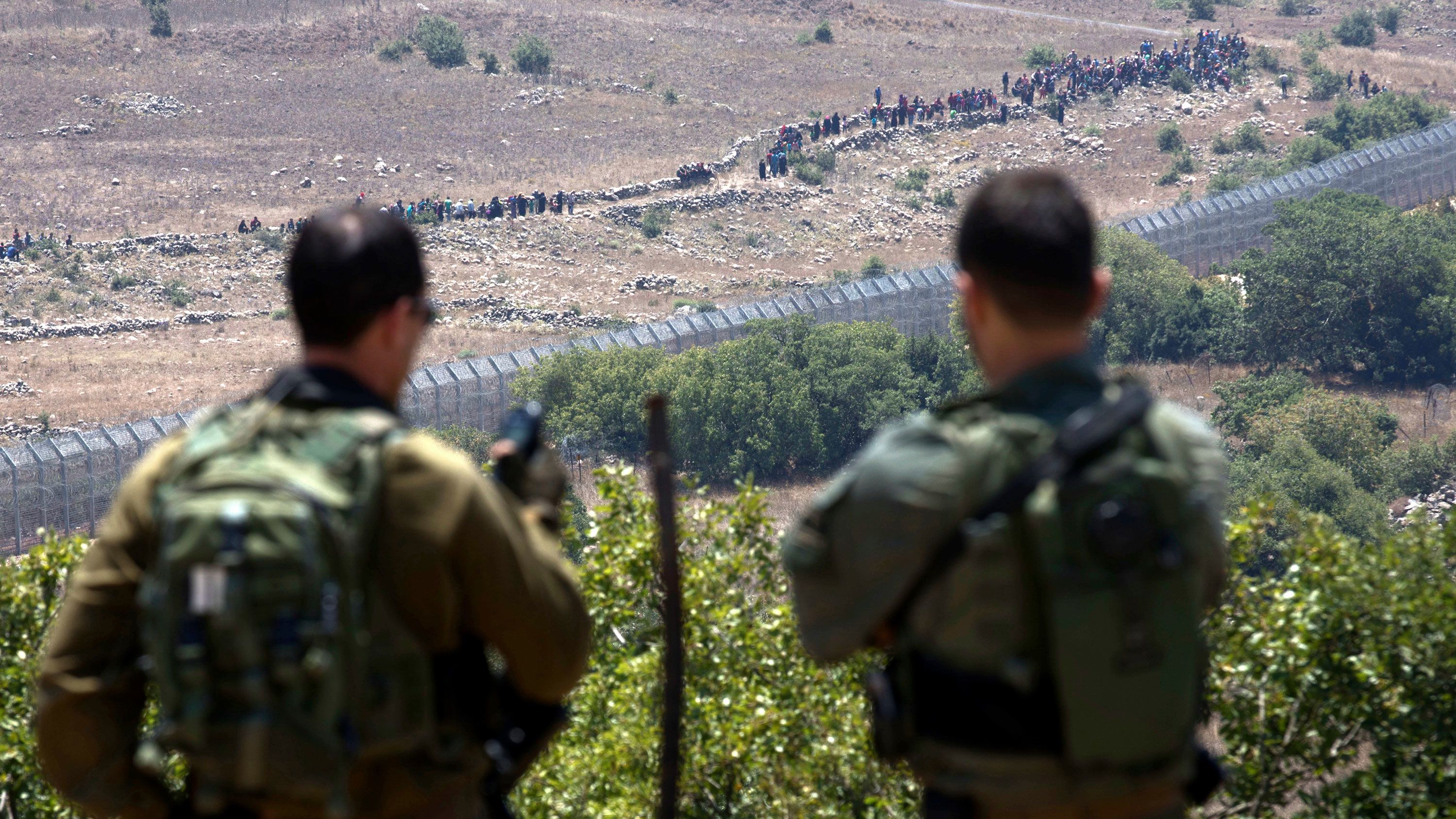 Israeli soldiers look on as Syrian refugees march towards the security fence in the Golan Heights on Tuesday.
