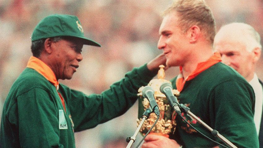 le capitaine de l'équipe de rugby d'Afrique du Sud, François Pienaar (D) est félicité par le Président de la République Sud-africaine, Nelson Mandela (G), après la victoire de son équipe en finale de la Coupe du Monde de Rugby face à la Nouvelle-Zélande le 24 juin 1995 à Johannesburg.South African rugby team captain, Francois Pienaar (R), is congratulated by South African President Nelson Mandela (L) after South Africa won the Rugby World Cup final against New Zealand 24 June 1995 in Johannesburg.        (Photo credit should read JEAN-PIERRE MULLER/AFP/Getty Images)