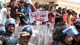 Iraqi security forces form a human barrier as protesters demonstrate against unemployment and a lack of basic services in the southern Iraqi city of Basra on July 15, 2018. The banner reads in Arabic "Basra's oil belongs to Basra". - Dozens of demonstrators were wounded today as the ongoing protests hit several Iraqi provinces including Basra, despite Prime Minister Haider al-Abadi announcing fresh funds and pledges of investment for the oil-rich but neglected region. (Photo by Haidar MOHAMMED ALI / AFP)        (Photo credit should read HAIDAR MOHAMMED ALI/AFP/Getty Images)