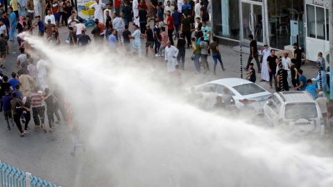 Iraqi security forces spray demonstrators with a water canon during protests in the city of Najaf, on Saturday, July 14.