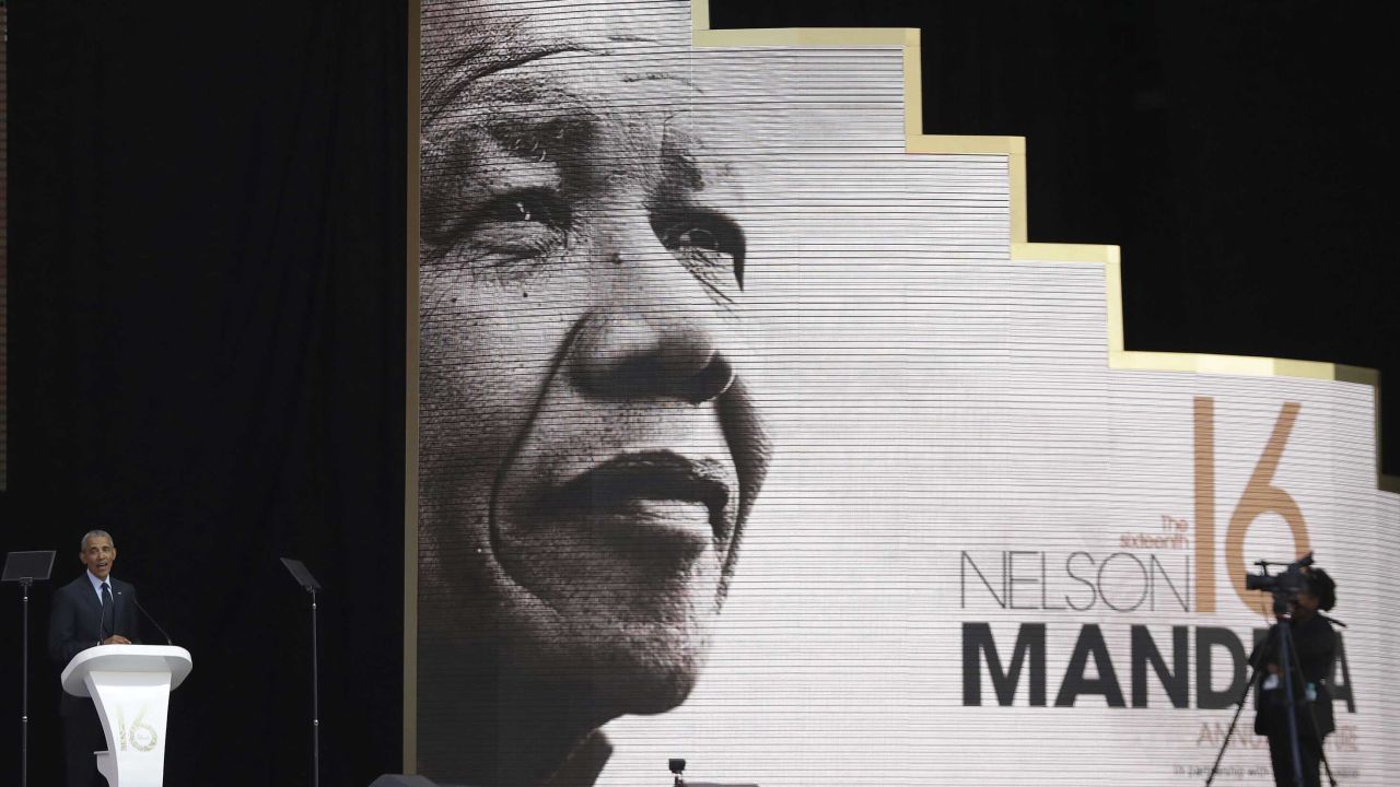 Obama speaking in front of an image of Nelson Mandela.