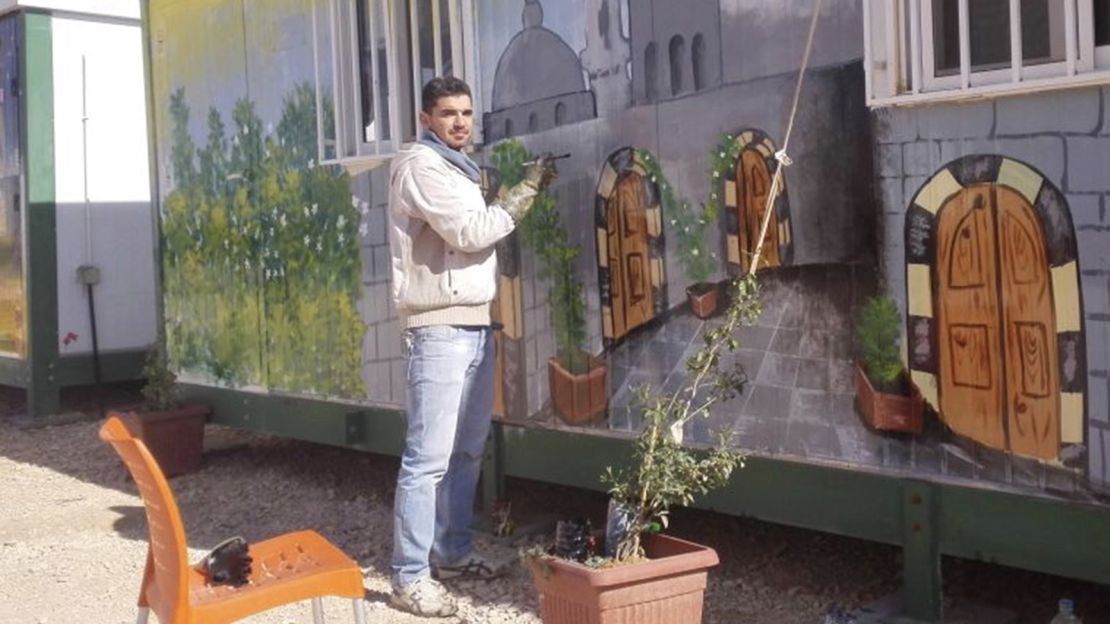 Syrian Mohamed Jokhadar painting on a caravan, adding some color to the Zaatari Refugee Camp. 