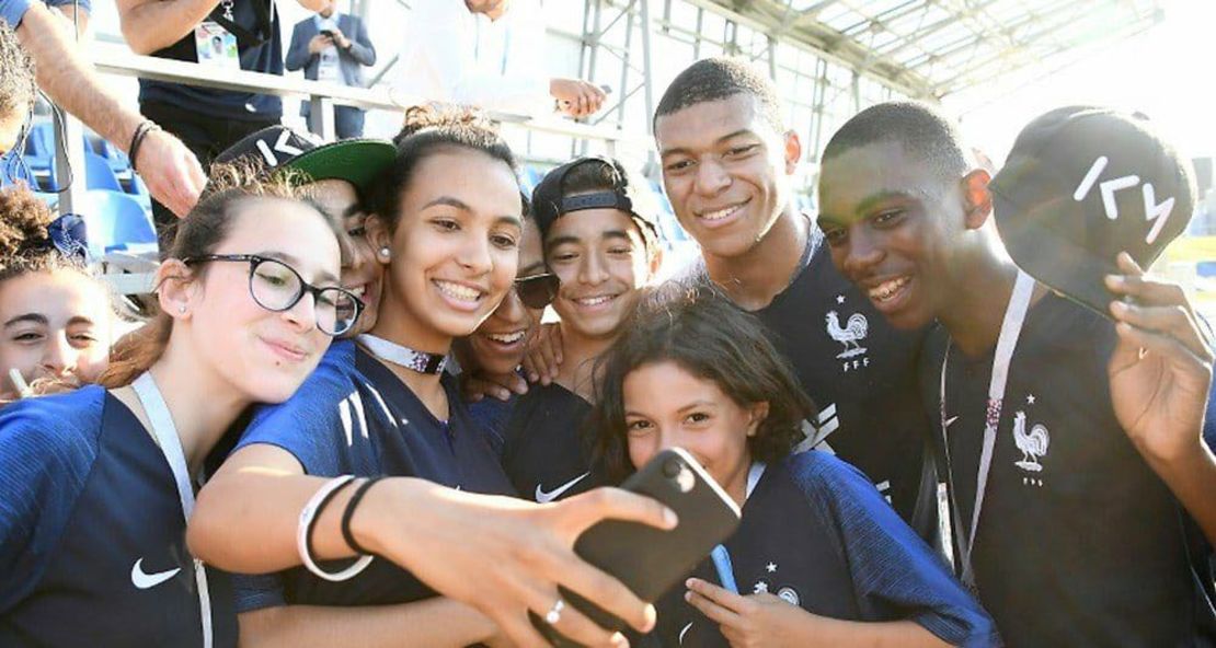 Kylian Mbappe poses for a photo with the pupils from school Jean Renoir.