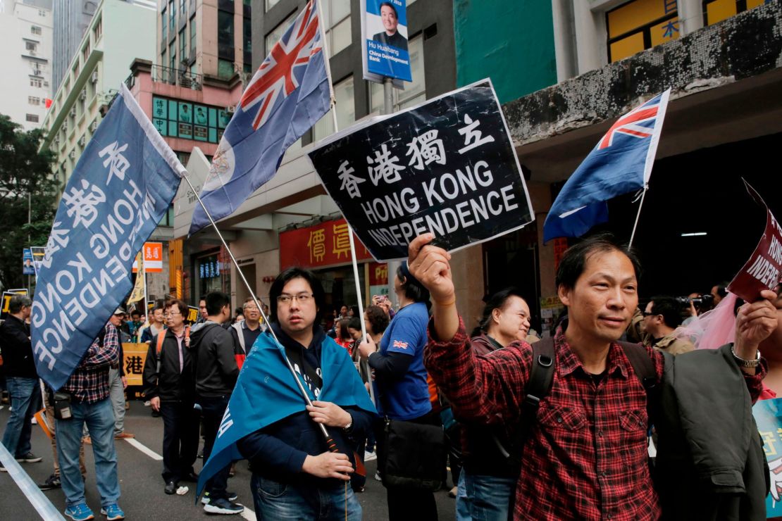Pro-independence protesters hold placard and wave Hong Kong colonial flags during a rally in Hong Kong on January 1, 2018.
