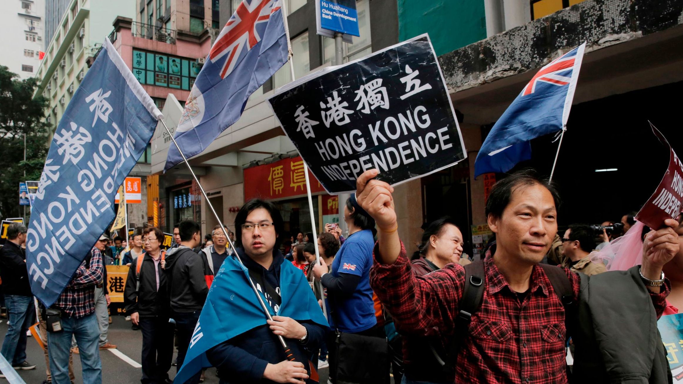 Pro-independence protesters hold placard and wave Hong Kong colonial flags during a rally in Hong Kong on January 1, 2018.