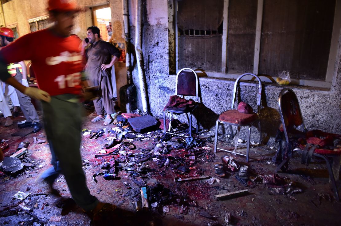 Pakistani security officials and volunteers search the site after a suicide bombing at an election rally in Peshawar on July 10, 2018.