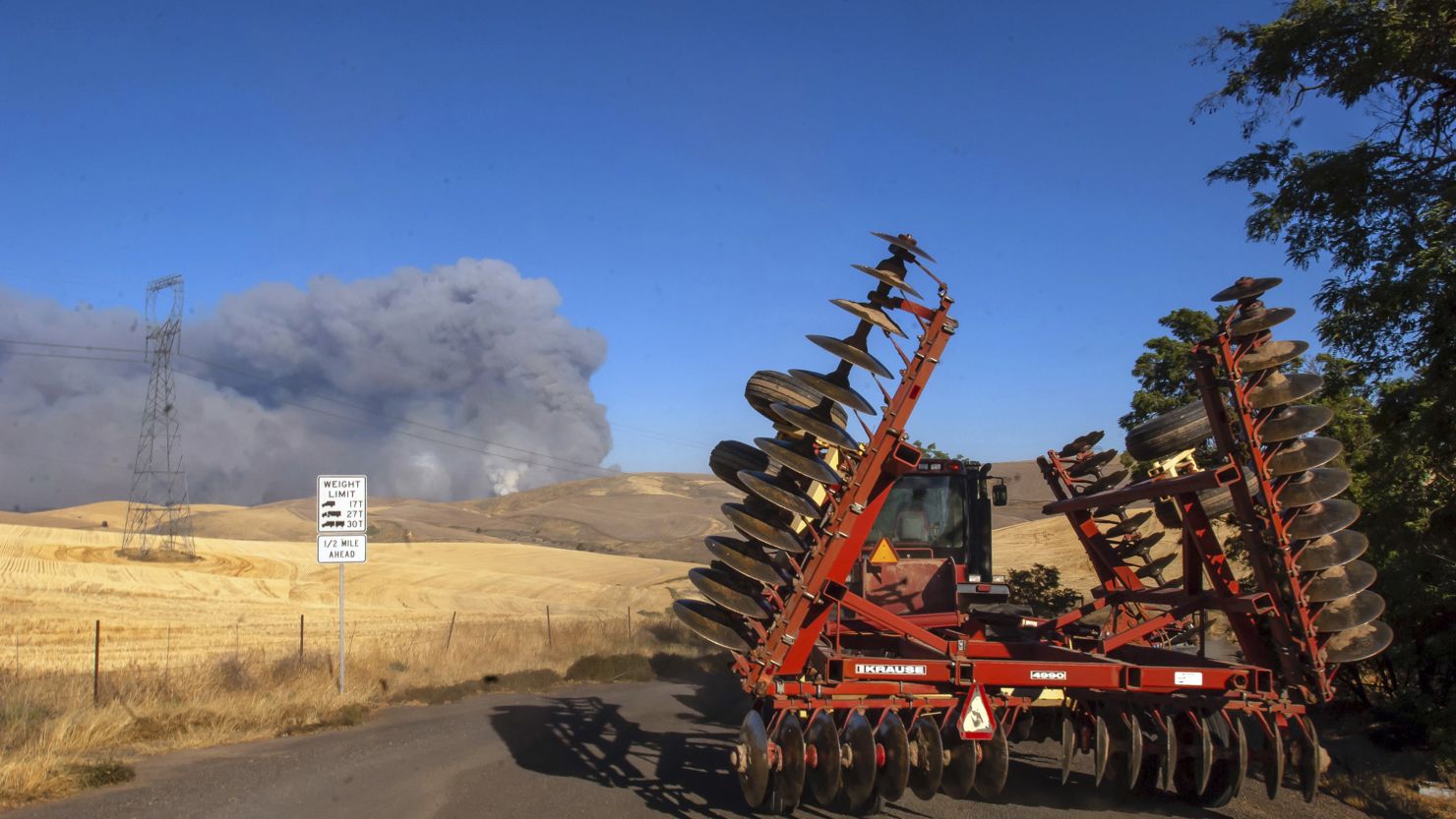 A tractor with a disc trailer rolls toward the fire on its way to cut fire lines.