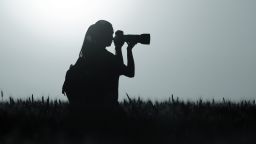 Silhouette of young girl taking nature photos in wheat field at night