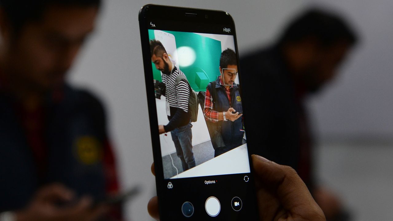 An Indian consumer holds the newly-launched Xiaomi Redmi Note 5 smartphone during a promotional event in New Delhi on February 14, 2018.