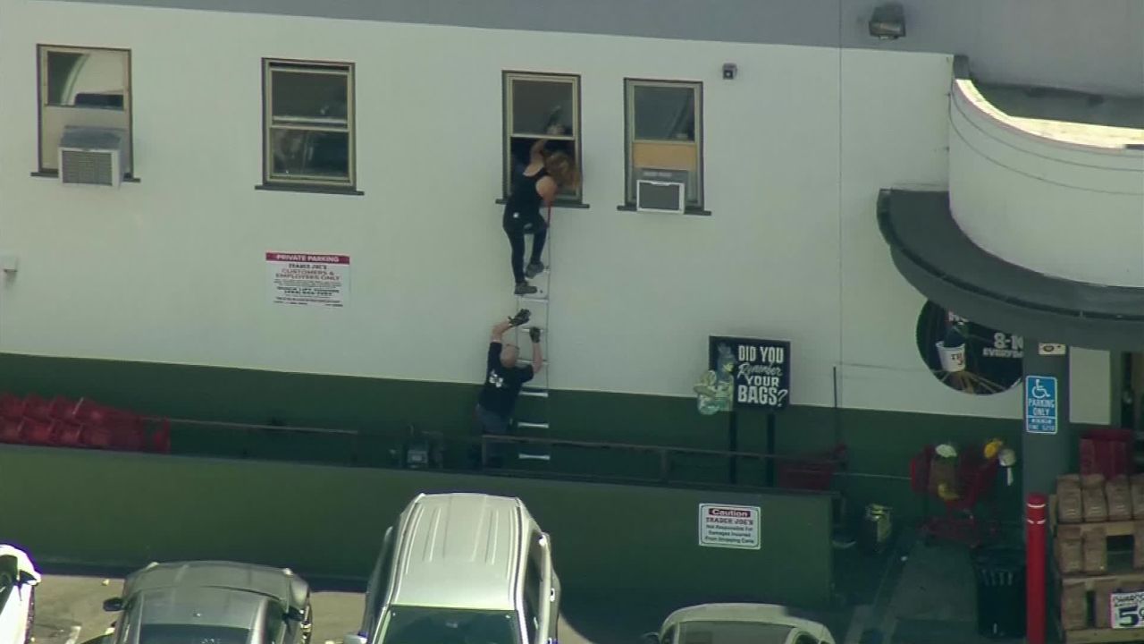 People crawl out of a back window at the Trader Joe's in Los Angeles.