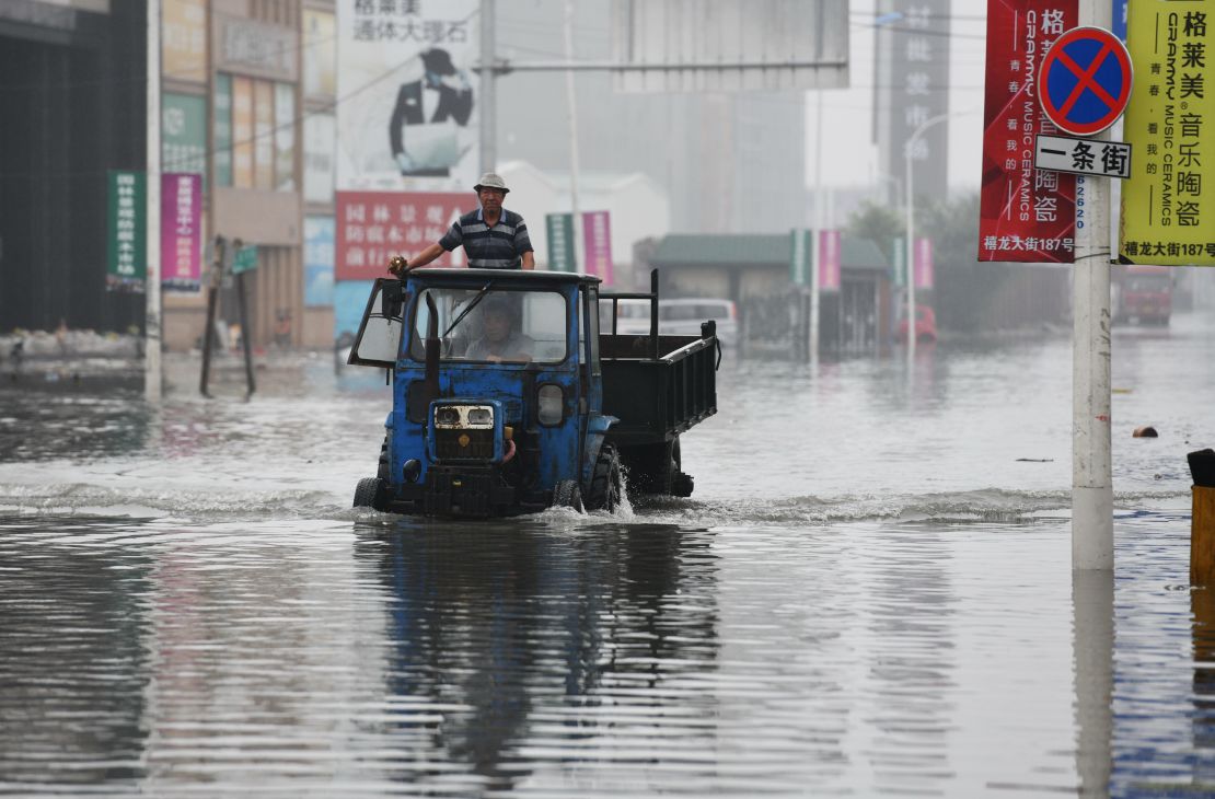 A local drives through a flooded street caused by heavy rainstorms in Harbin city, northeast China's Heilongjiang province on July 19.