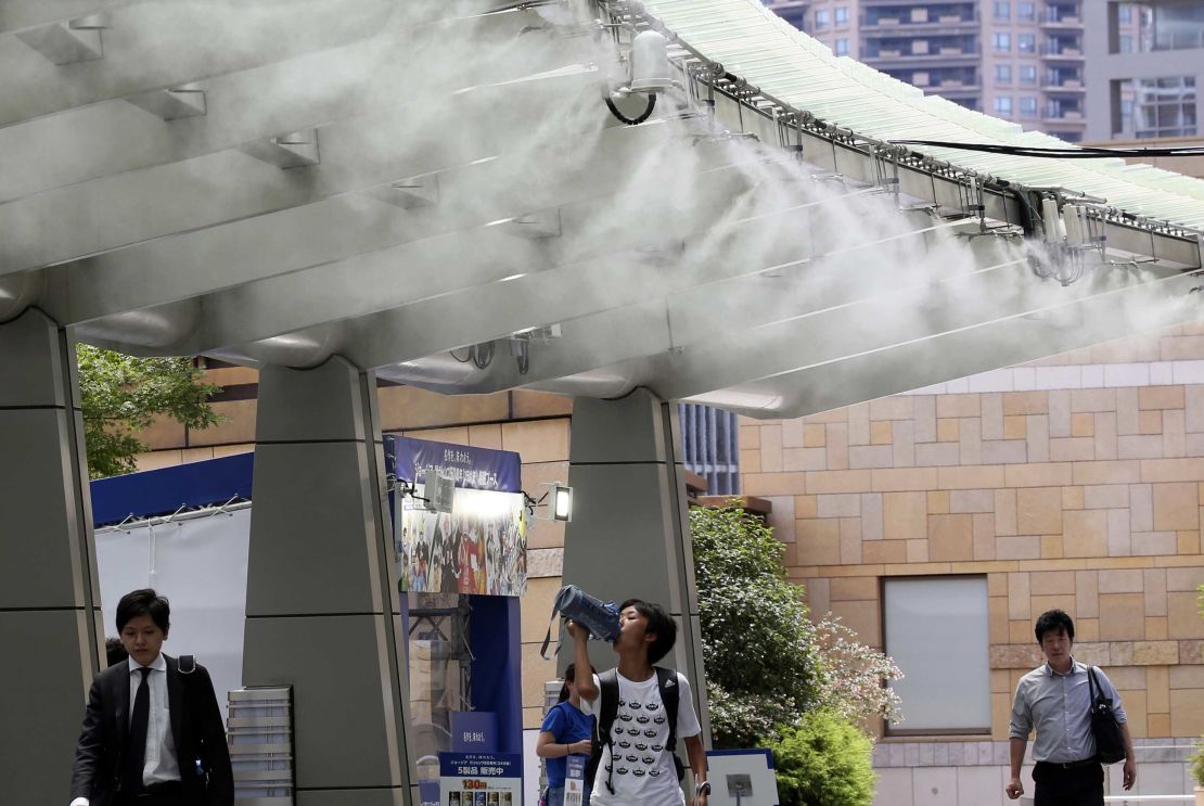 People cool down under the cooling mist spot in Tokyo on July 23. 