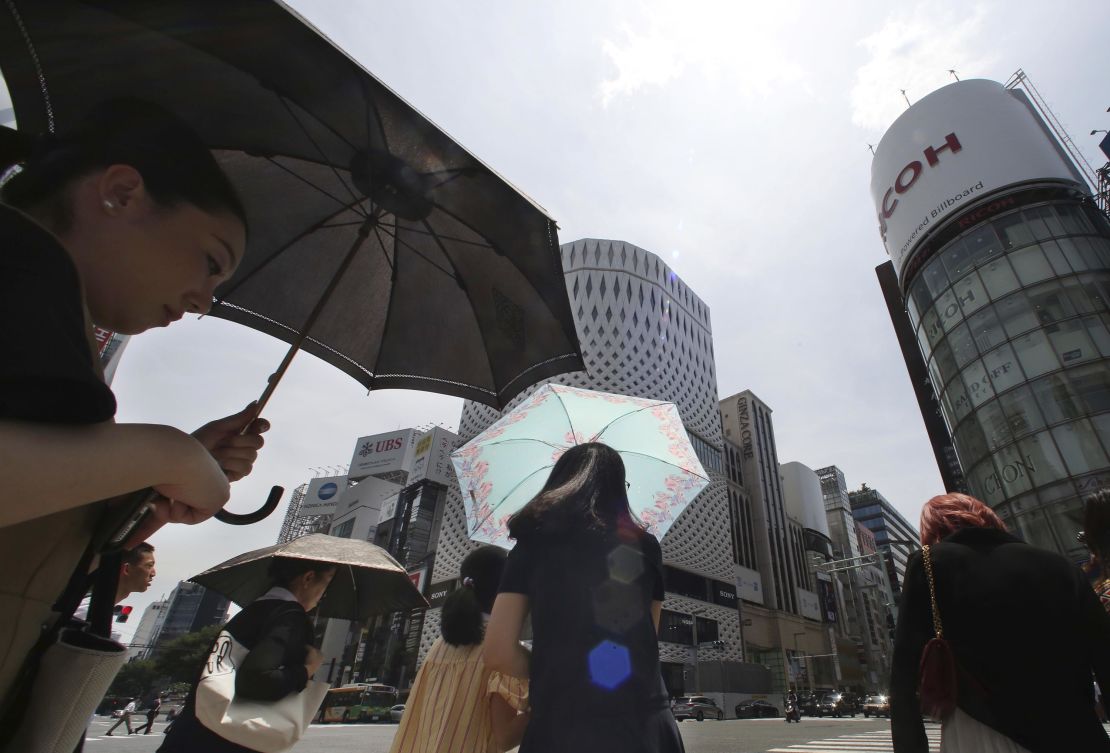 People shade themselves from the heat of the sun with umbrellas in Tokyo on July 23, 2018.