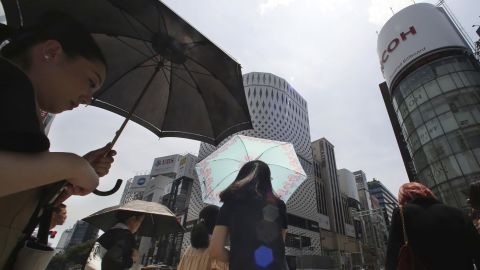 People shade themselves from the heat of the sun with umbrellas in Tokyo on July 23, 2018.
