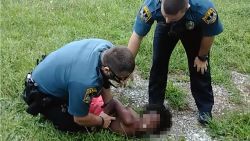 An image taken from a Facebook video shows two officers restraining a 10-year-old boy.
