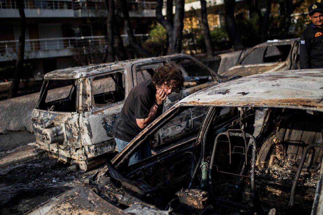A woman searches for her dog Tuesday after the fire in Mati, near the Greek capital of Athens.
