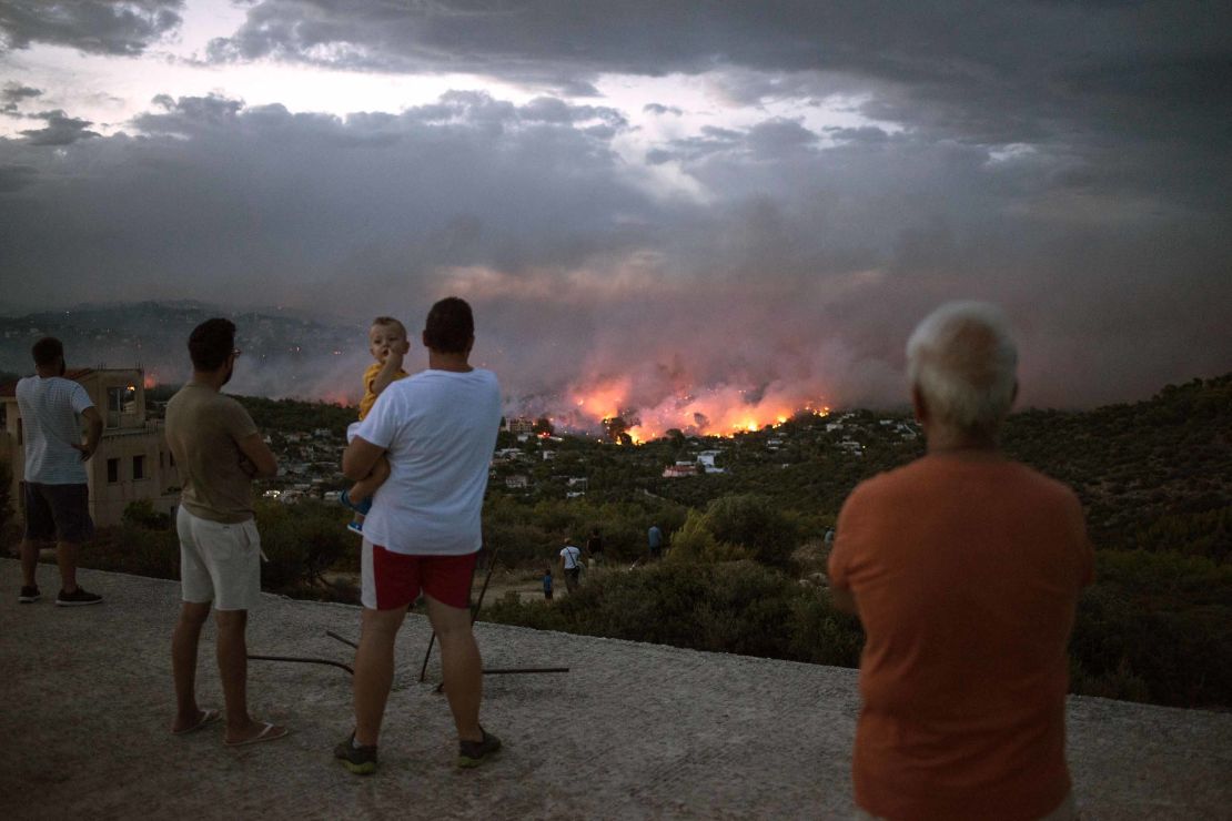 People watch a wildfire in Rafina on Monday.