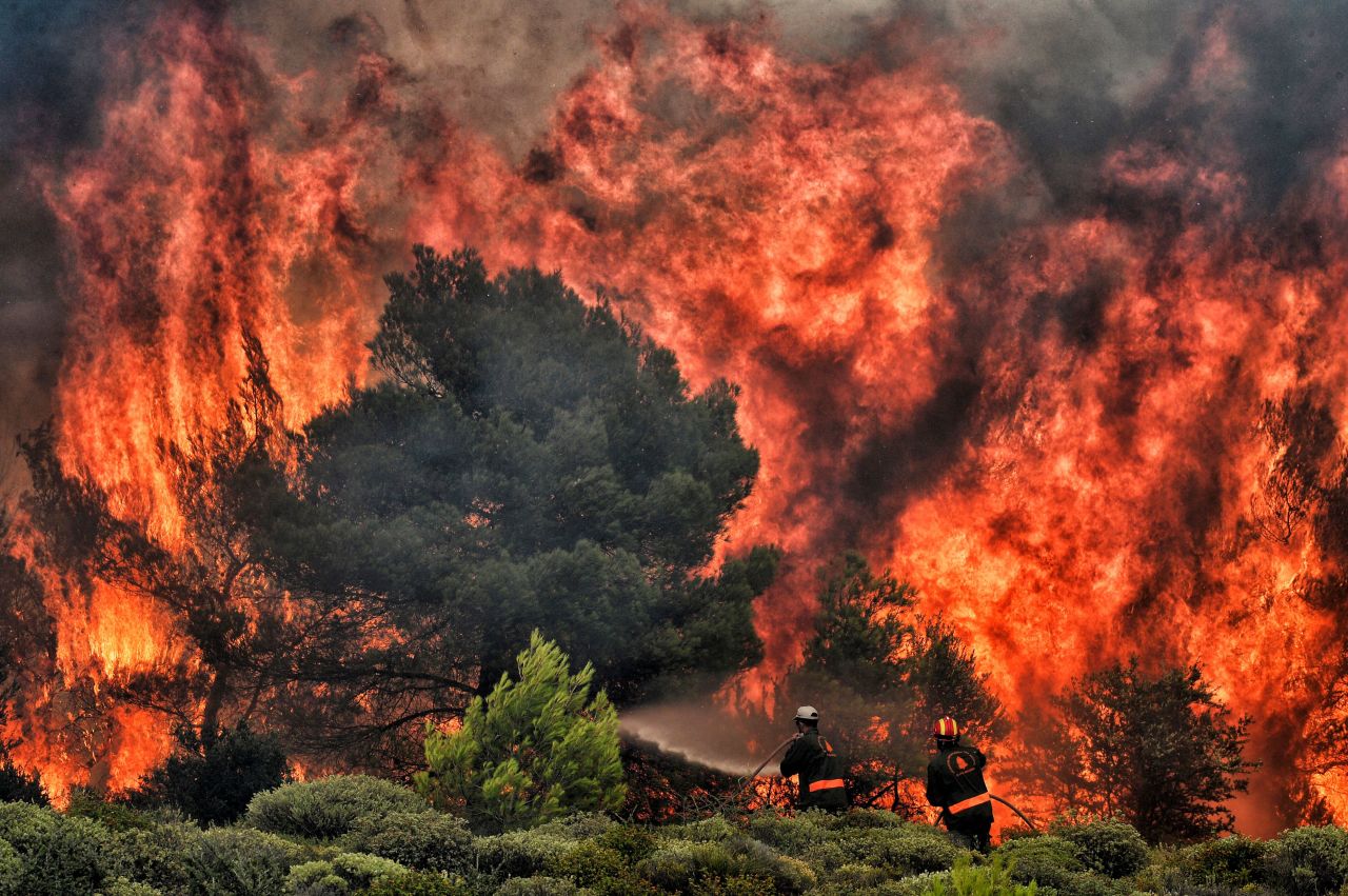 Firefighters try to extinguish flames in Kineta on July 24.