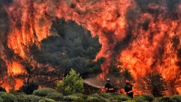 Firefighters try to extinguish flames during a wildfire at the village of Kineta, near Athens, on July 24, 2018. - Raging wildfires killed 74 people including small children in Greece, devouring homes and forests as terrified residents fled to the sea to escape the flames, authorities said Tuesday. (Photo by ANGELOS TZORTZINIS / AFP)        (Photo credit should read ANGELOS TZORTZINIS/AFP/Getty Images)