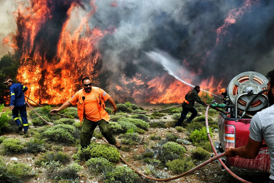 Firefighters and volunteers try to extinguish flames in Kineta, Greece, on Tuesday, July 24.
