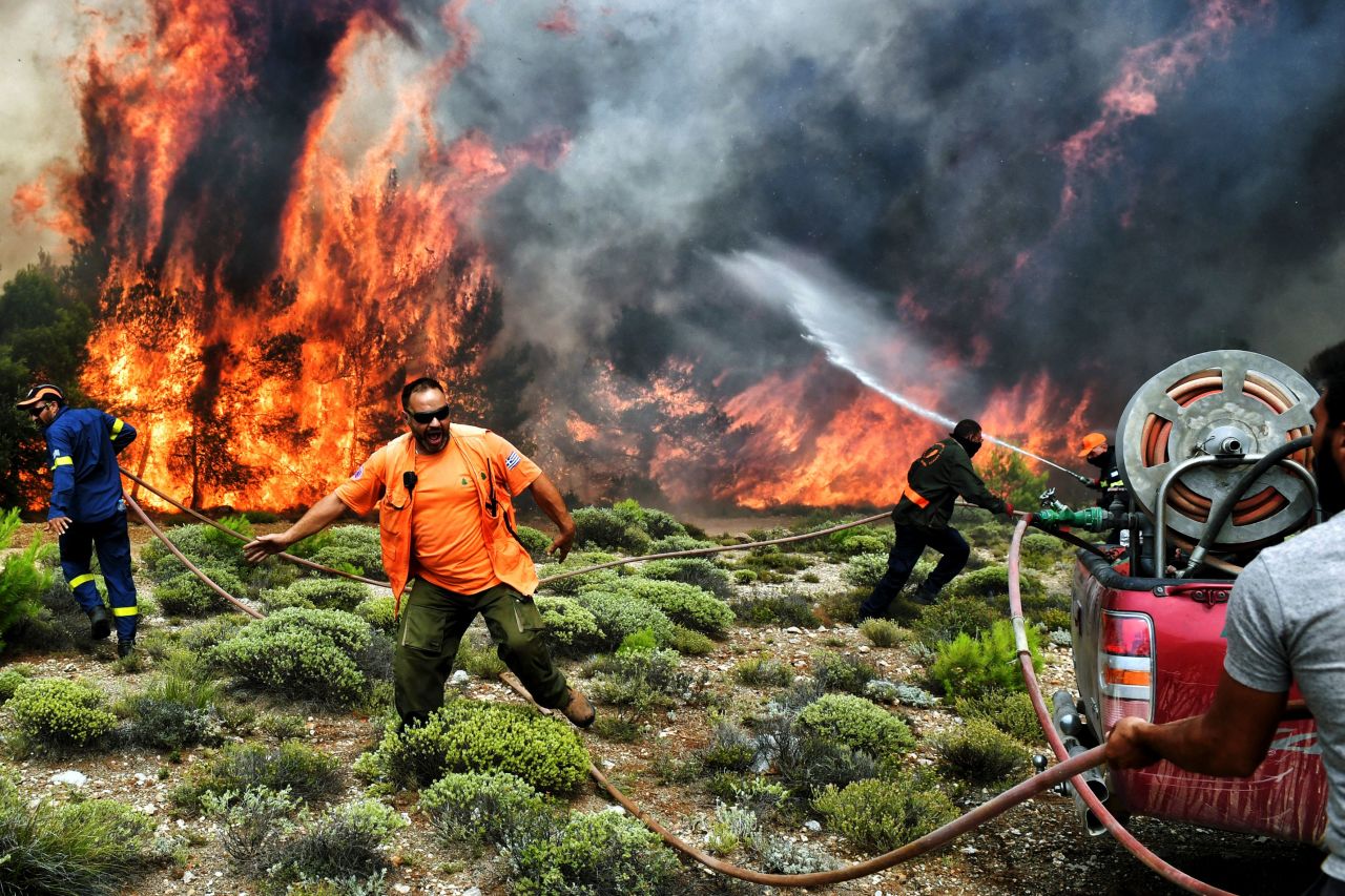 Firefighters and volunteers try to extinguish flames in Kineta, Greece, on Tuesday, July 24.