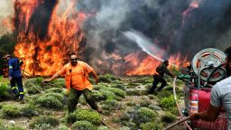 Firefighters and volunteers try to extinguish flames during a wildfire at the village of Kineta, near Athens, on July 24, 2018. - Raging wildfires killed 74 people including small children in Greece, devouring homes and forests as terrified residents fled to the sea to escape the flames, authorities said Tuesday. (Photo by ANGELOS TZORTZINIS / AFP)        (Photo credit should read ANGELOS TZORTZINIS/AFP/Getty Images)
