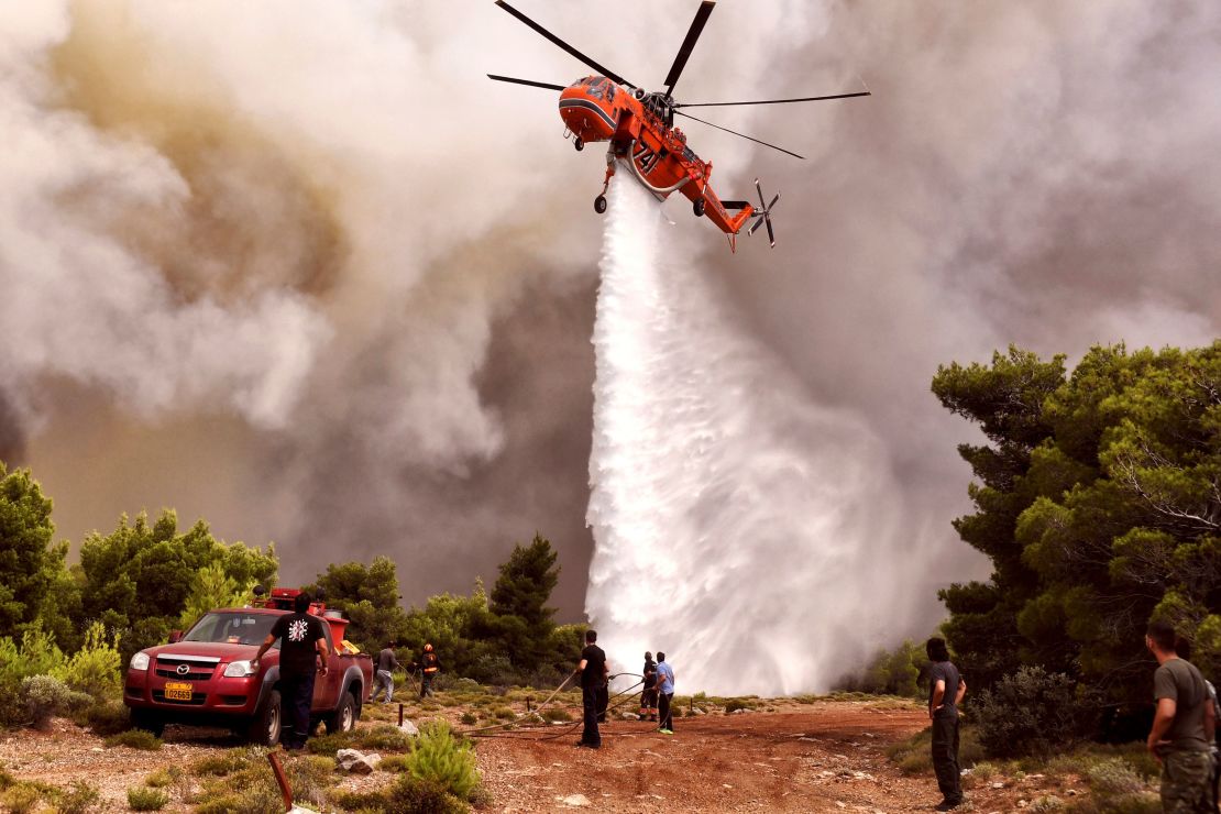 A firefighting helicopter drops water to extinguish flames Tuesday in the village of Kineta.