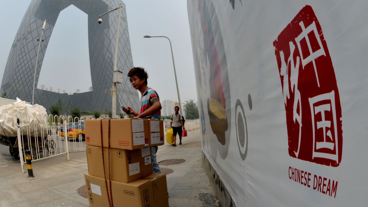 A Chinese migrant worker stands beside a 'Chinese Dream' poster near the CCTV Tower in the Central Business District of Beijing on August 6, 2013.  Chinese President Xi Jinping has urged China to pursue the "Chinese dream" but experts say behind the grandiose words he is single-minded in his aim to bolster Communist Party rule.    AFP PHOTO/Mark RALSTON        (Photo credit should read MARK RALSTON/AFP/Getty Images)