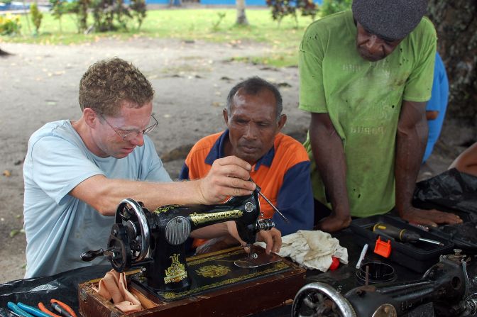 During their travels, the Giffords have exchanged time on the boat and other acts of goodwill for recipes and cultural experiences. Here Jamie helps a local in Papua New Guinea repair a sewing machine.