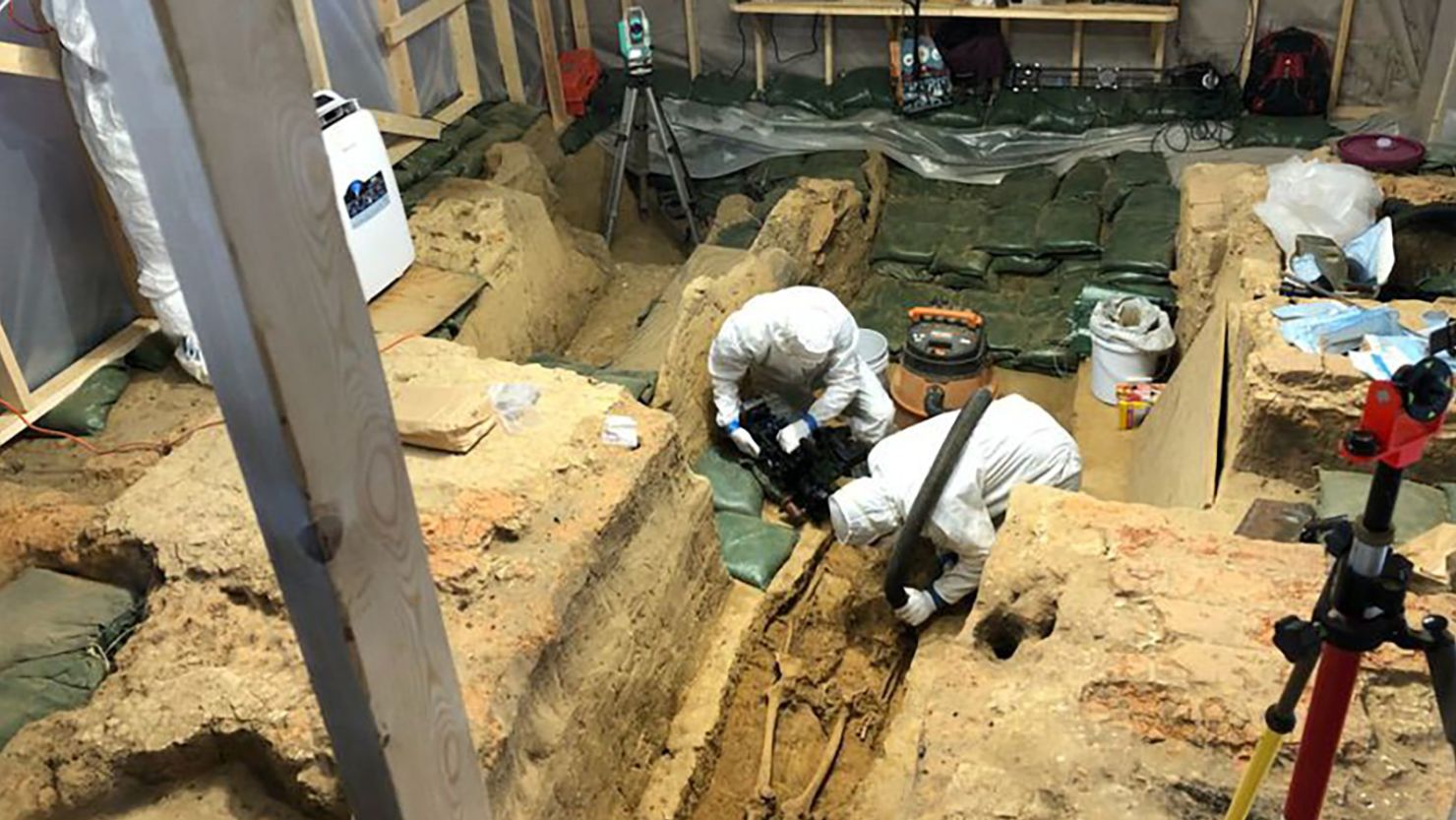 Scientists don full-body suits to minimize disturbance of the precious artifacts uncovered in a 1617 church in Jamestown, Virginia, where a newly found skeleton awaits identification. 