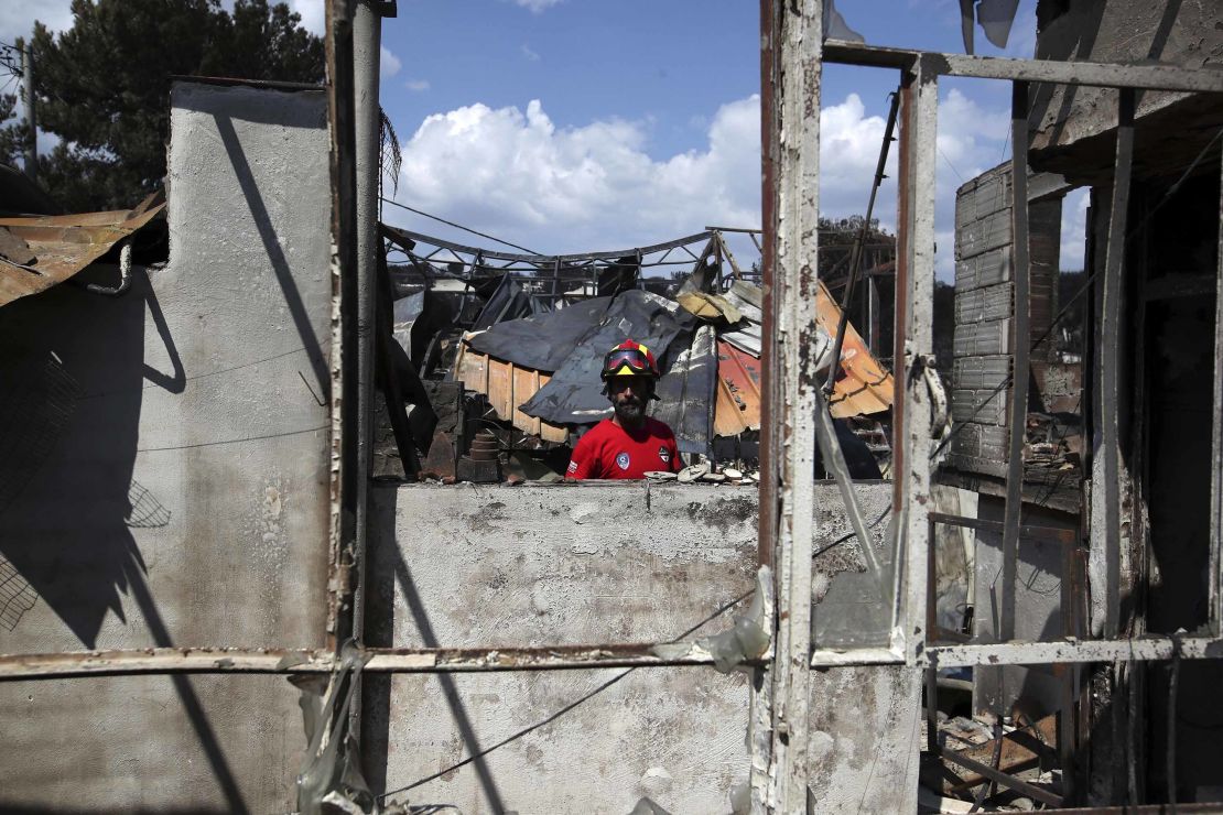 A member of a rescue team searches a burned house Wednesday in Mati.