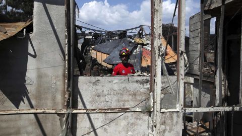 A member of a rescue team searches a burned house Wednesday in Mati.