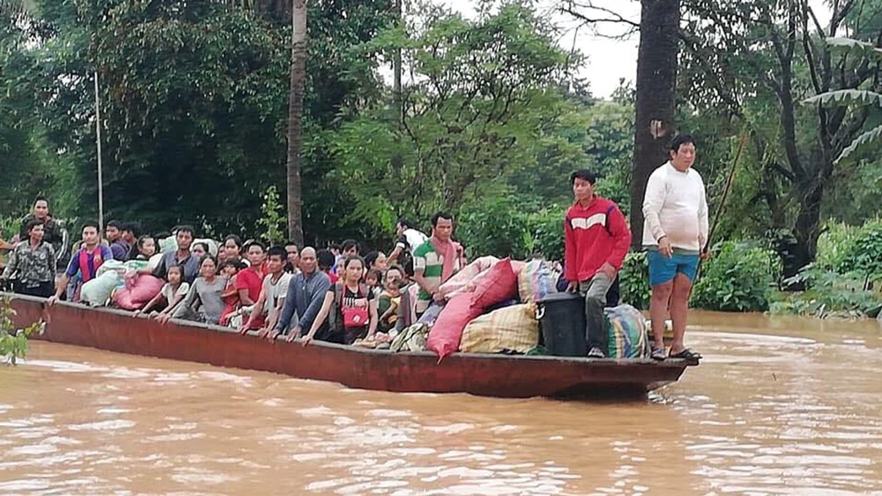 In this Tuesday photo, people are evacuated in the floodwaters from the collapsed dam.