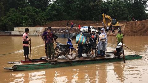 People use a makeshift ferry to cross the swollen Xe Khong river on July 25.