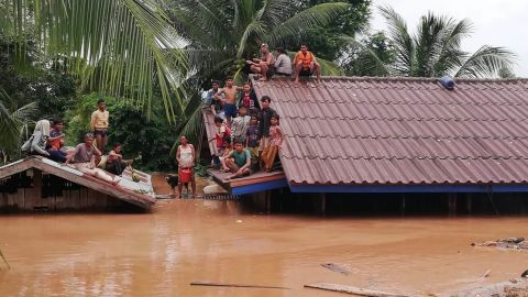 People are stranded on  rooftops Tuesday after a dam under construction collapsed in Laos.