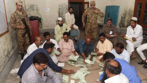 Pakistani soldiers stand guard Wednesday as election officials count ballots at a Lahore polling station.
