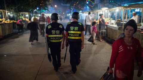This picture taken on June 25, 2017 shows police patrolling in a night food market near the Id Kah Mosque in Kashgar in China's Xinjiang Uighur Autonomous Region, a day before the Eid al-Fitr holiday.