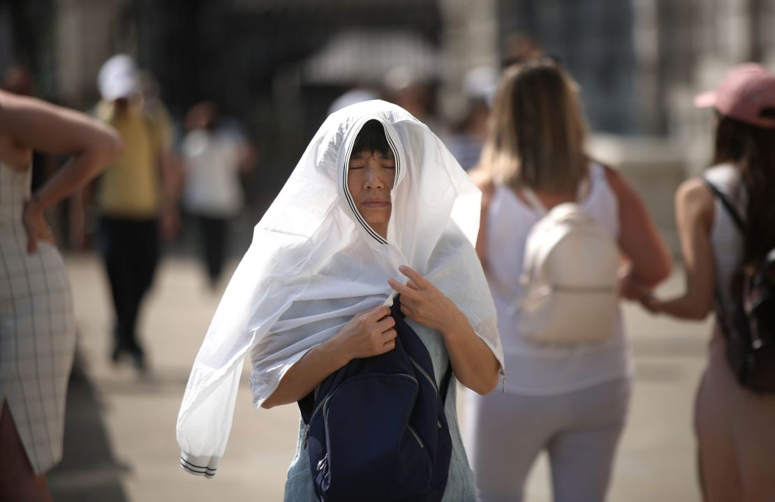 A person covers up from the sun in London amid the driest start to a summer since modern records began in 1961.