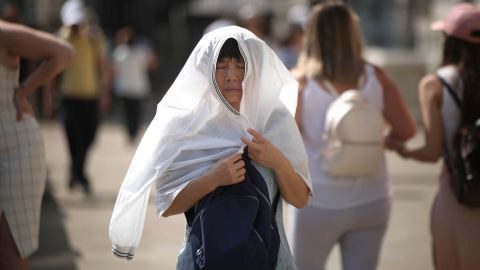 A person covers up from the sun in London amid the driest start to a summer since modern records began in 1961.